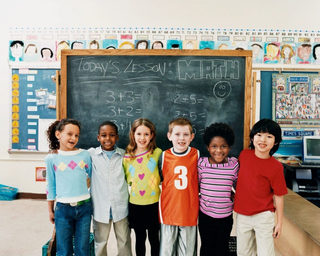 children standing in front of chalk board