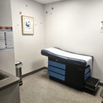 Exam room with exam table, gray floors, and white walls